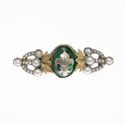 Broche en argent à la fleur de Lys sur fond émaillé vert, décoré de perles sur monture et feuillage en or.